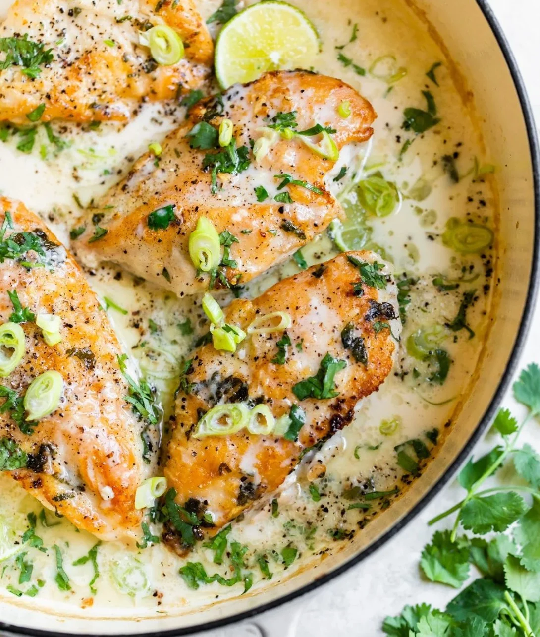 Creamy coconut lime chicken garnished with lime slices and herbs