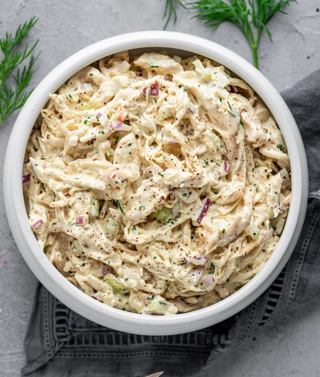 Creamy Keto Chicken Salad bowl garnished with herbs.