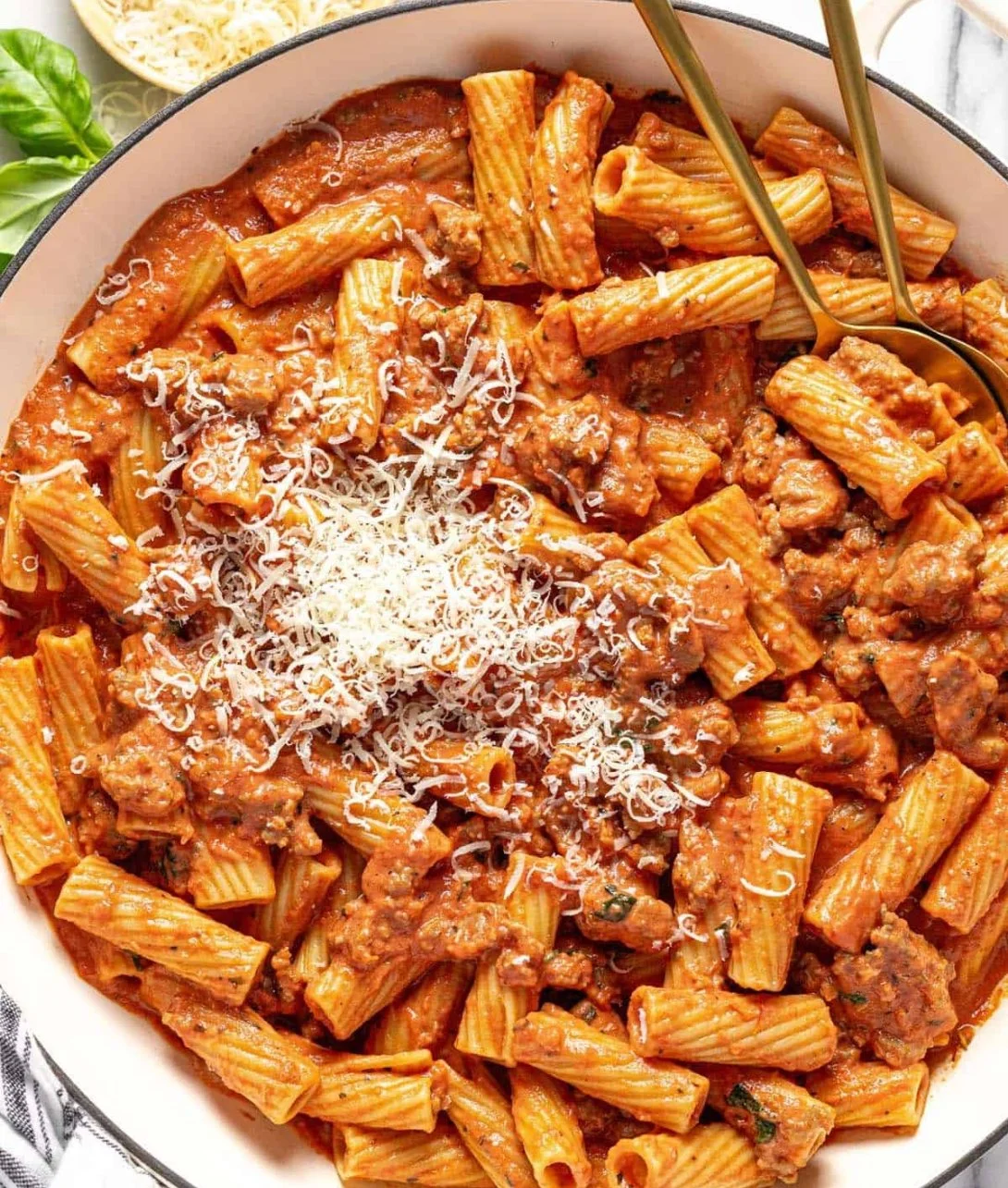 Bowl of creamy sausage rigatoni pasta topped with herbs and cheese