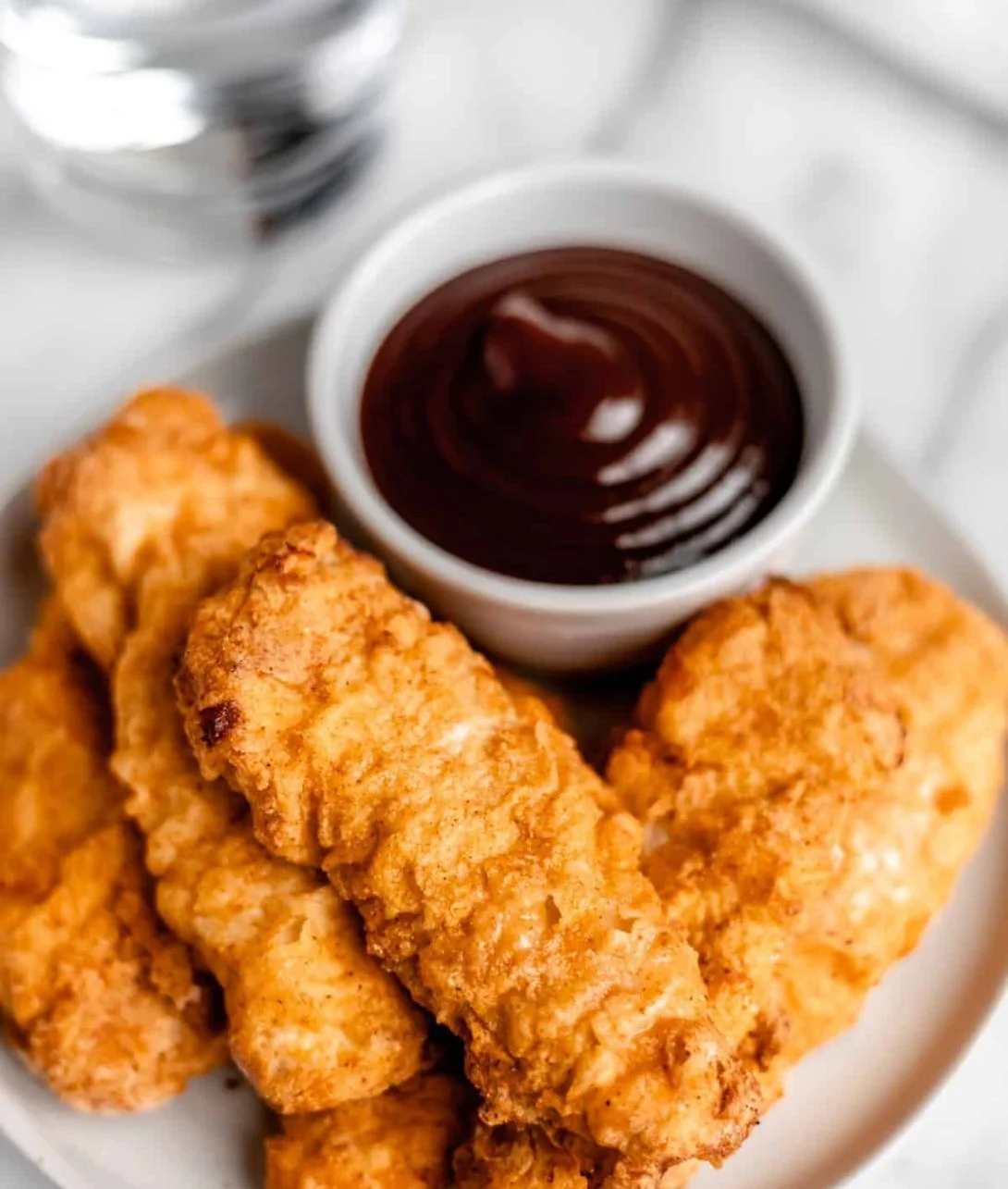 Crispy air fryer chicken tenders served on a plate with dipping sauce.