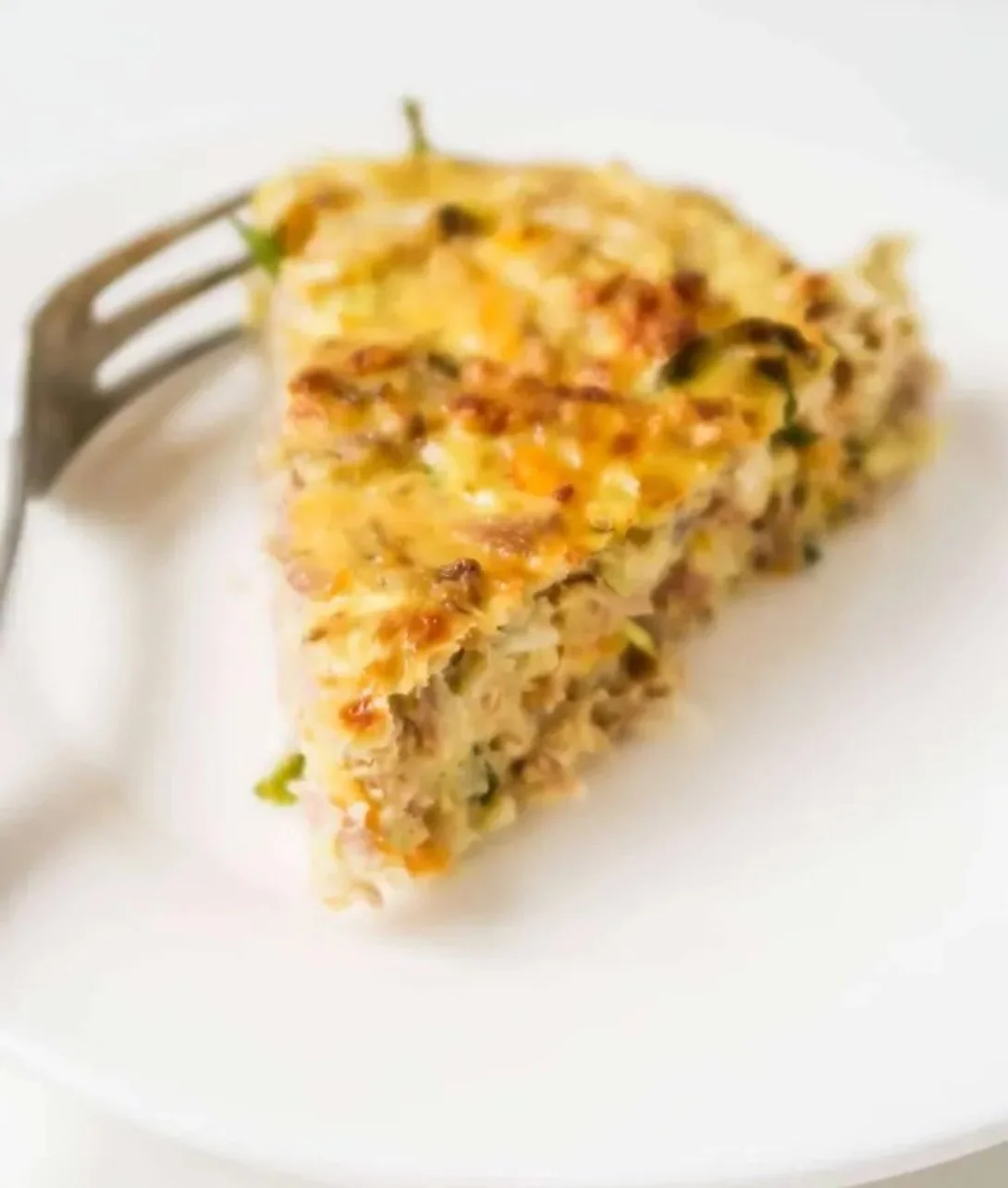 Crustless tuna breakfast quiche served on a plate with fresh herbs