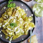 A plate of Green Chilaquiles topped with avocado and cilantro.
