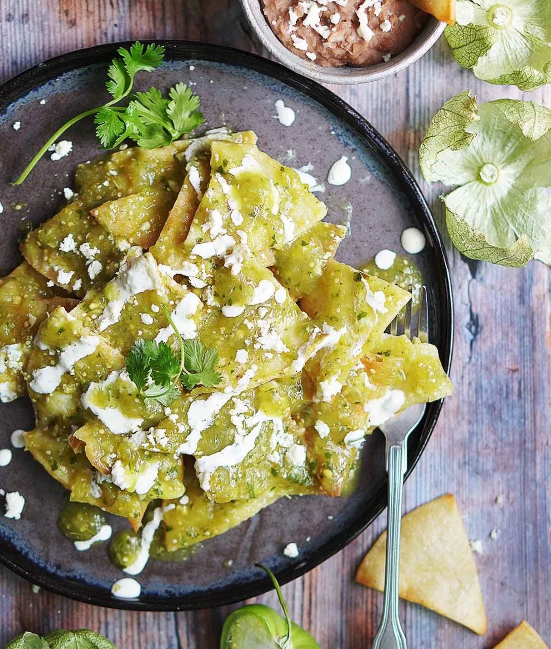 A plate of Green Chilaquiles topped with avocado and cilantro.