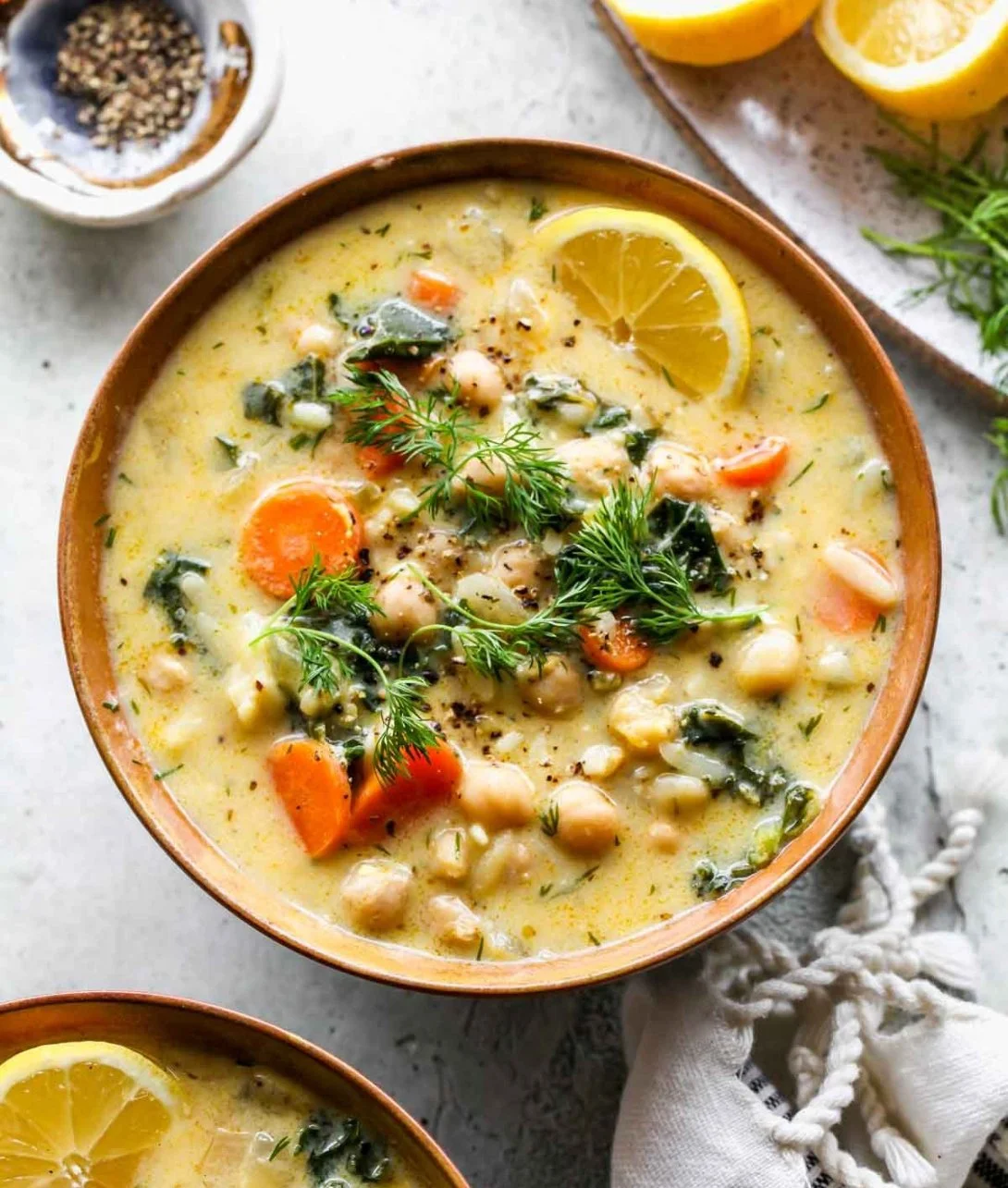 Bowl of Lemony Greek Chickpea Soup garnished with herbs and lemon slices.