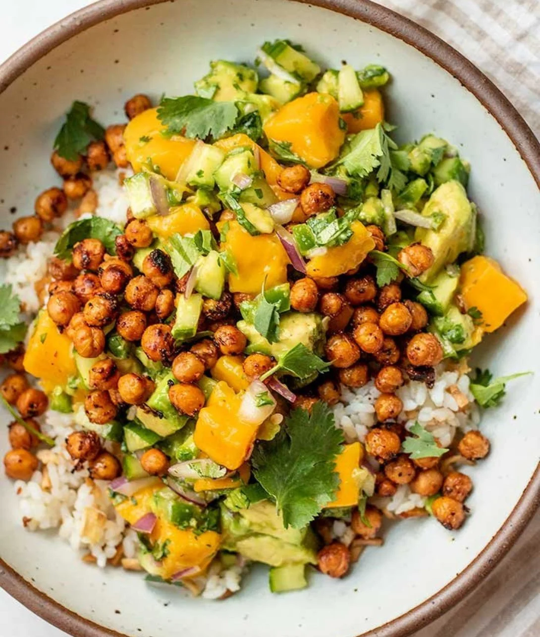 Colorful Mango Chickpea Salad garnished with fresh herbs and dressing