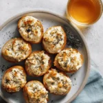 Mini tuna melts served on a plate with melted cheese and fresh herbs