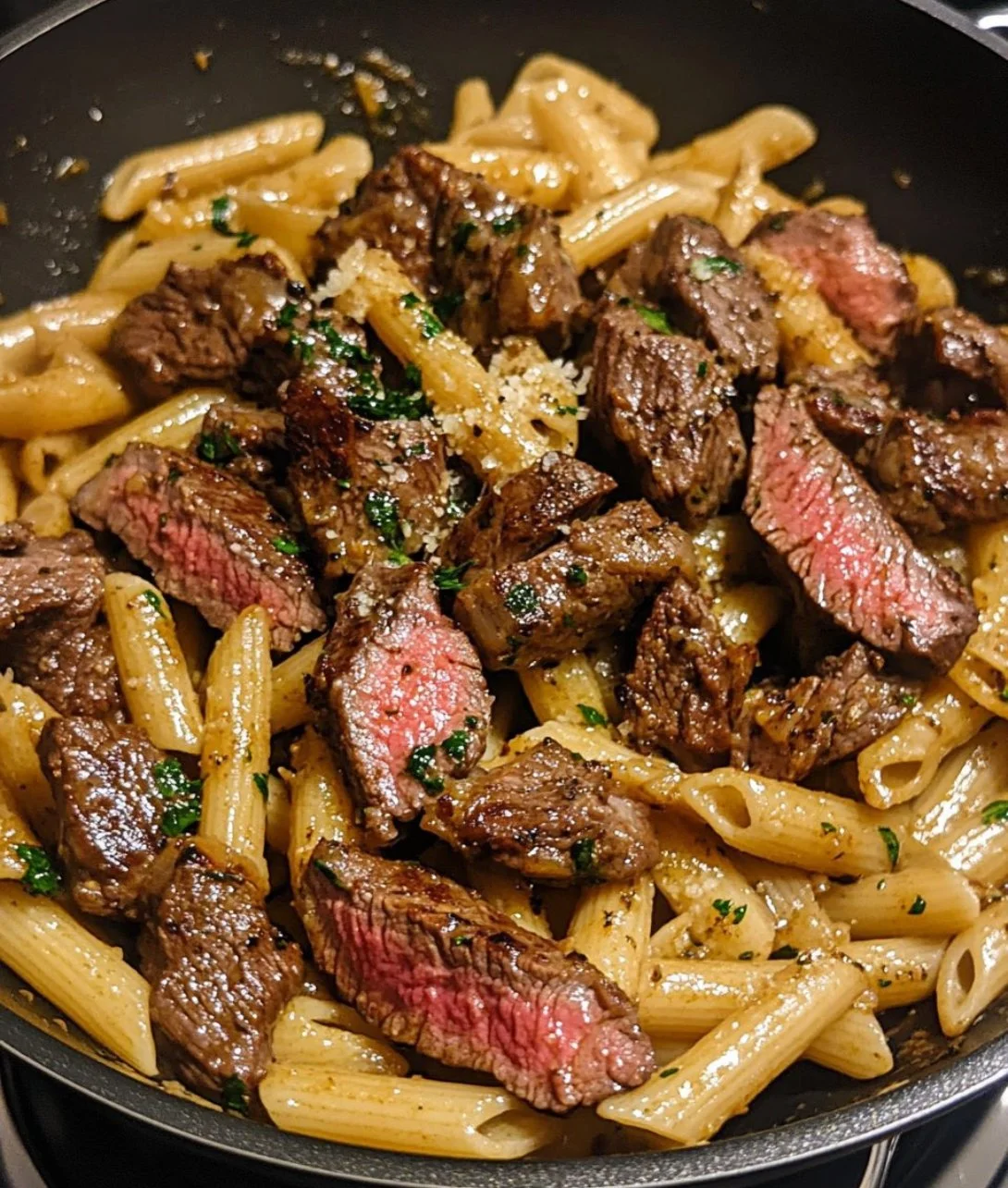 One-skillet spicy garlic butter Parmesan steak pasta garnished with herbs
