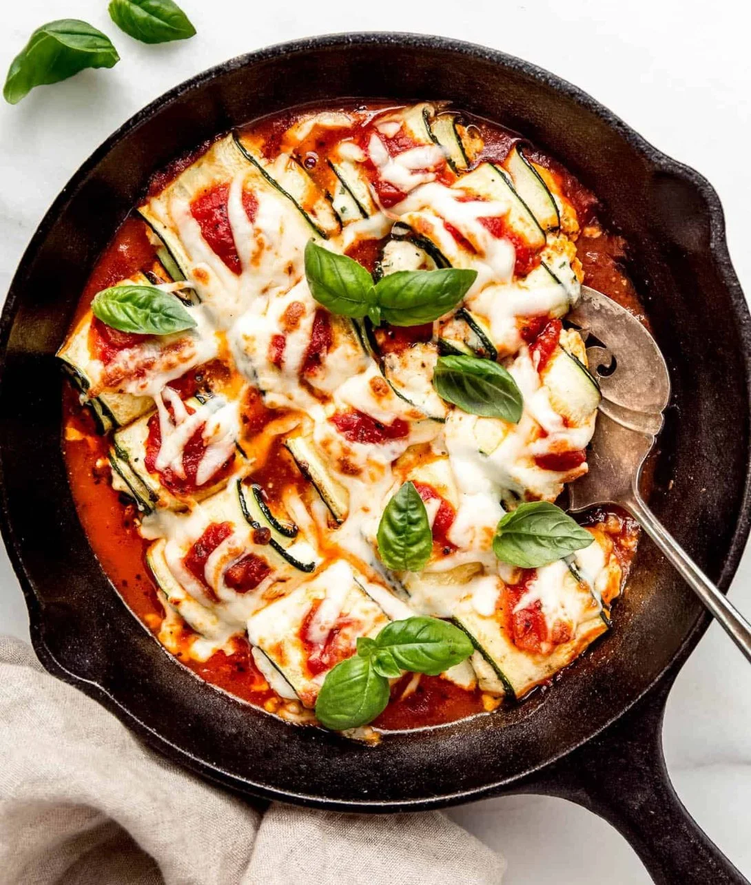 Ricotta stuffed zucchini rolls garnished with herbs and served on a plate