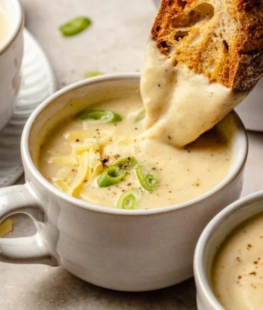Bowl of creamy roasted garlic cheddar cauliflower soup garnished with herbs