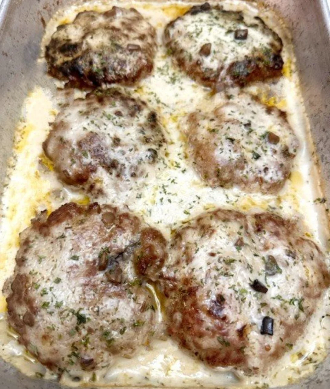 Smothered hamburger steak topped with gravy, served with sides on a plate
