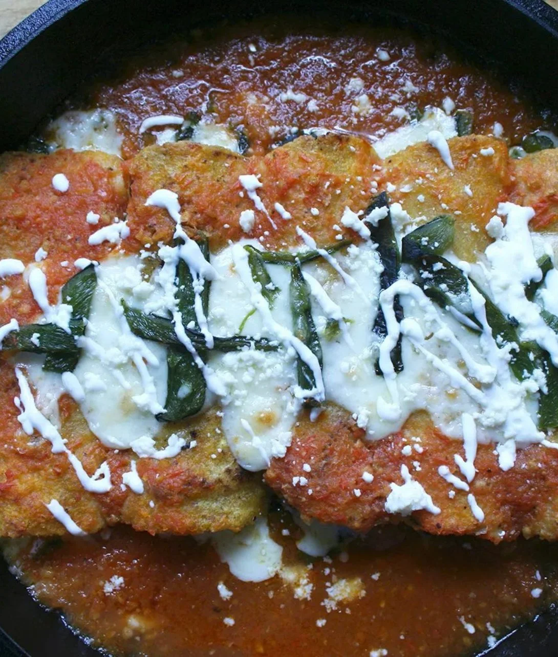 Plate of stuffed chile enchiladas garnished with fresh herbs and cheese