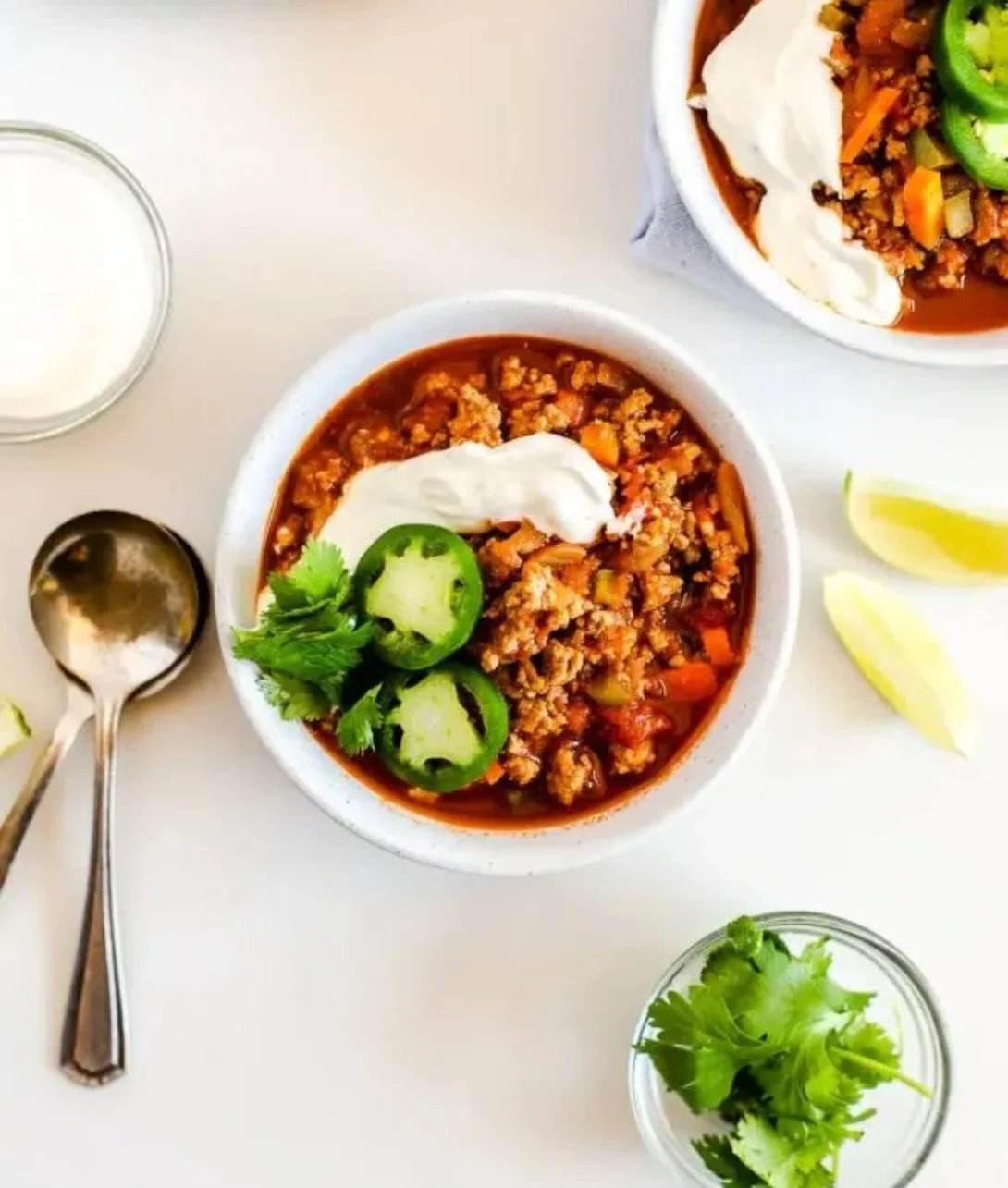 Bowl of flavorful turkey chili topped with fresh herbs.