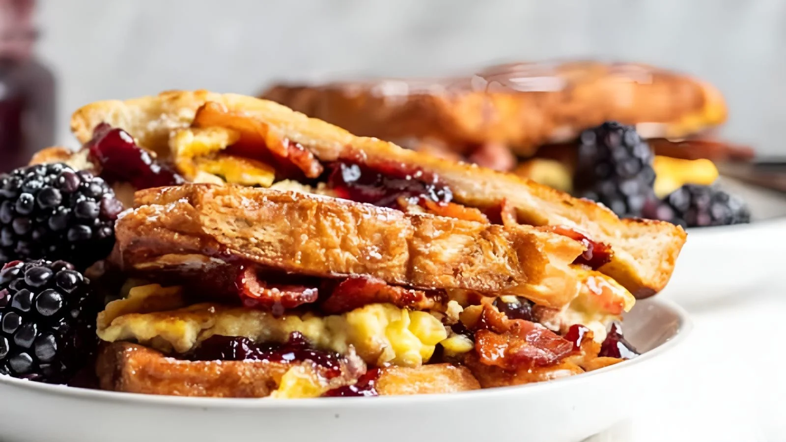 Bacon Blackberry French Toast Sandwich topped with syrup and berries