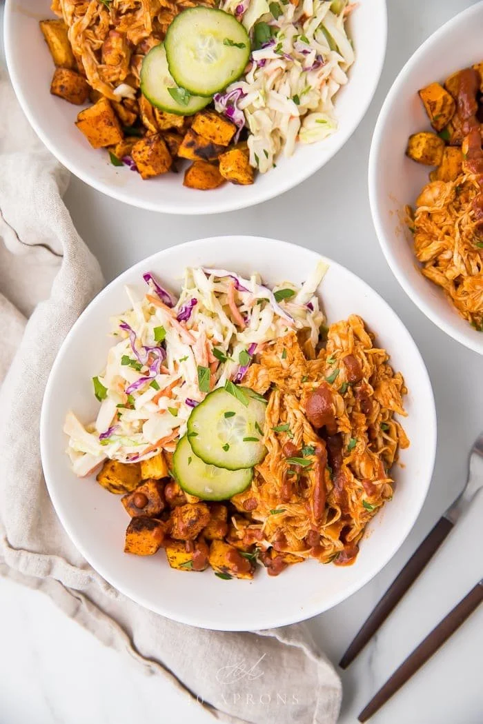 BBQ chicken bowls with sweet potatoes and coleslaw served in a vibrant dish