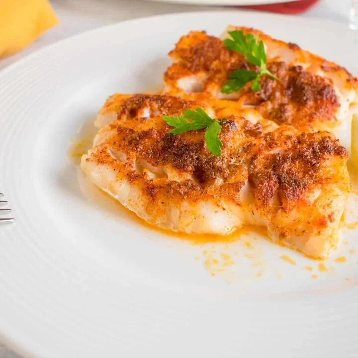 Delicious broiled cod served with lemon and herbs on a platter.