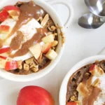 Creamy apple baked oatmeal in a bowl garnished with fresh apple slices and cinnamon.