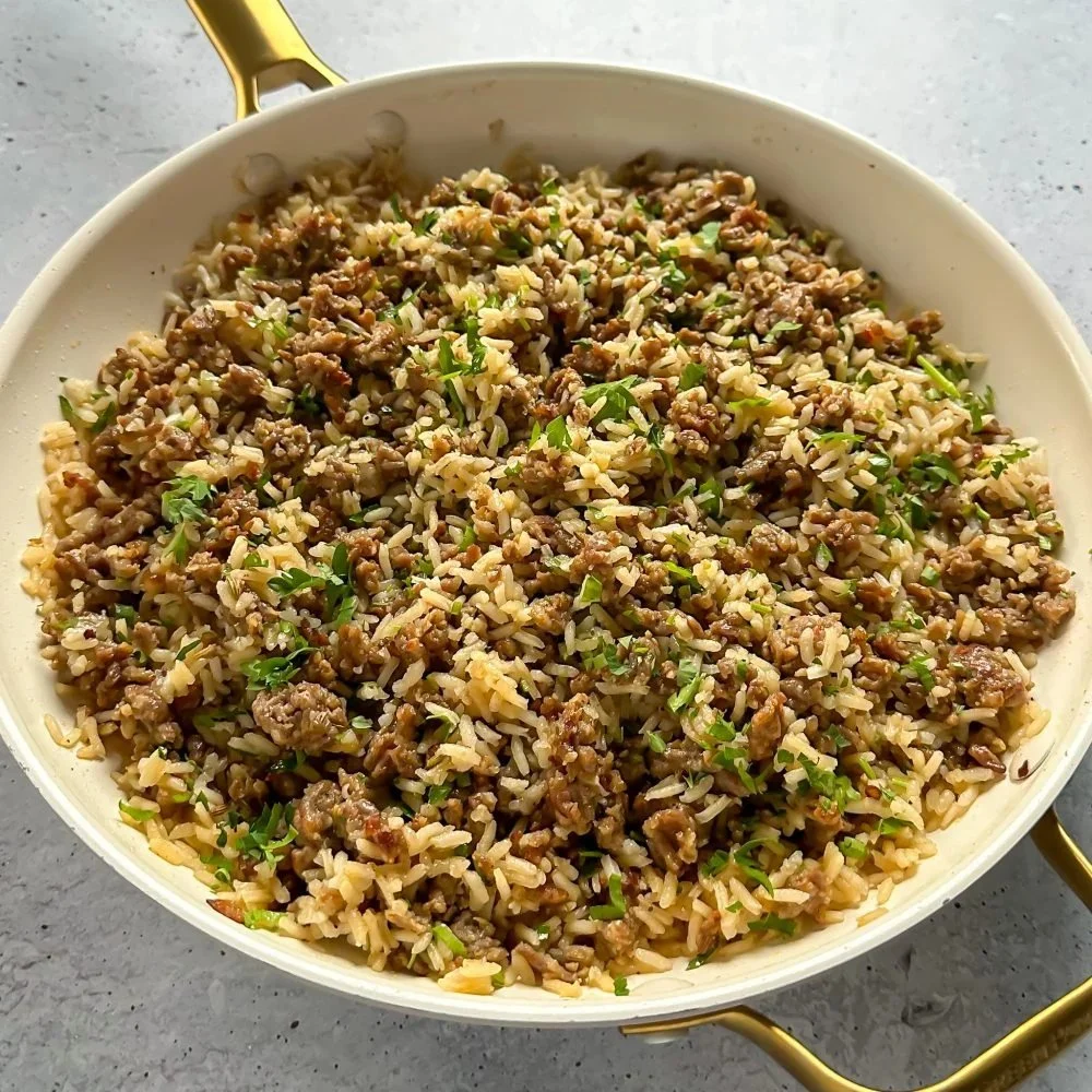 Delicious Italian sausage rice dish garnished with herbs on a plate.