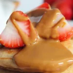 Fluffy Lotus Biscoff pancakes topped with syrup and crushed Biscoff cookies