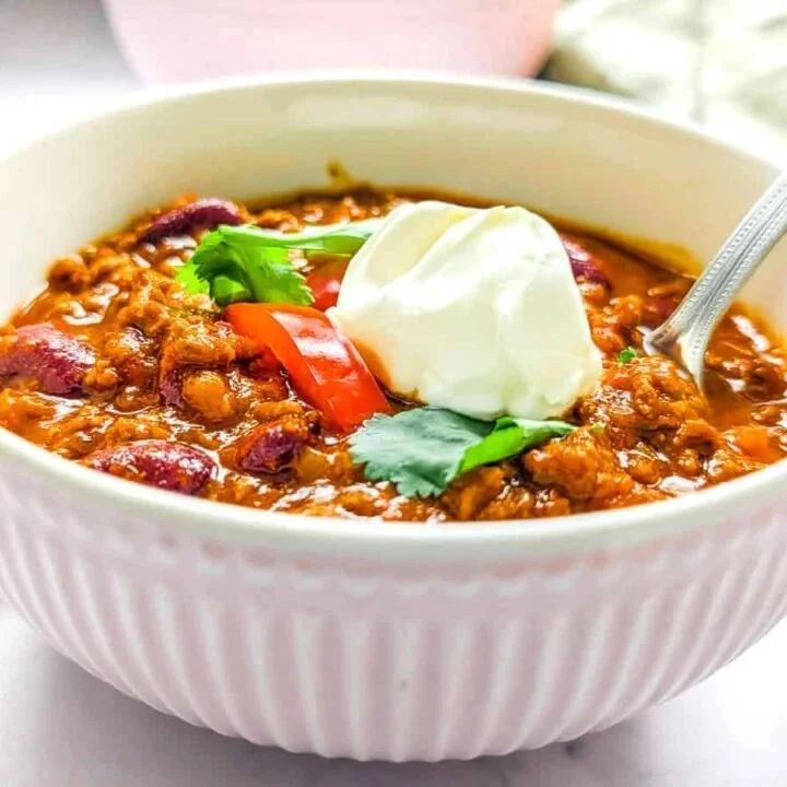 Pressure cooker chili con carne topped with fresh herbs in a bowl