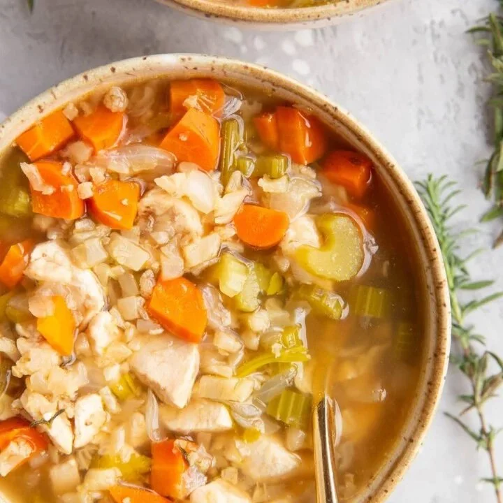 Bowl of slow cooker chicken and cauliflower rice soup with fresh herbs